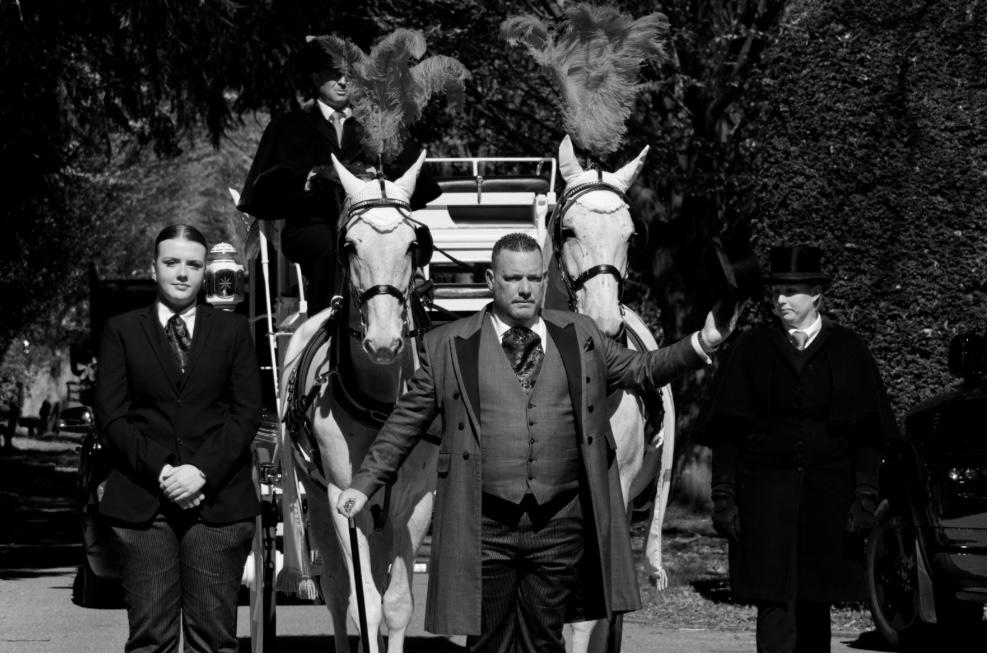 Mathew K Sutton standing respectfully outside a chapel in his funeral attire, Kent